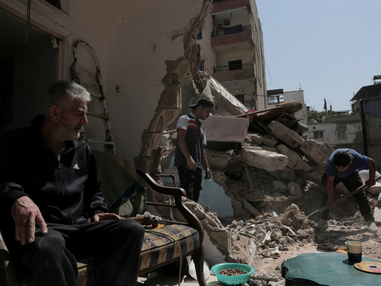 A 60-year-old looks on as people clean his house, damaged in an Israeli strike, in Lebanon. Photo: Reuters