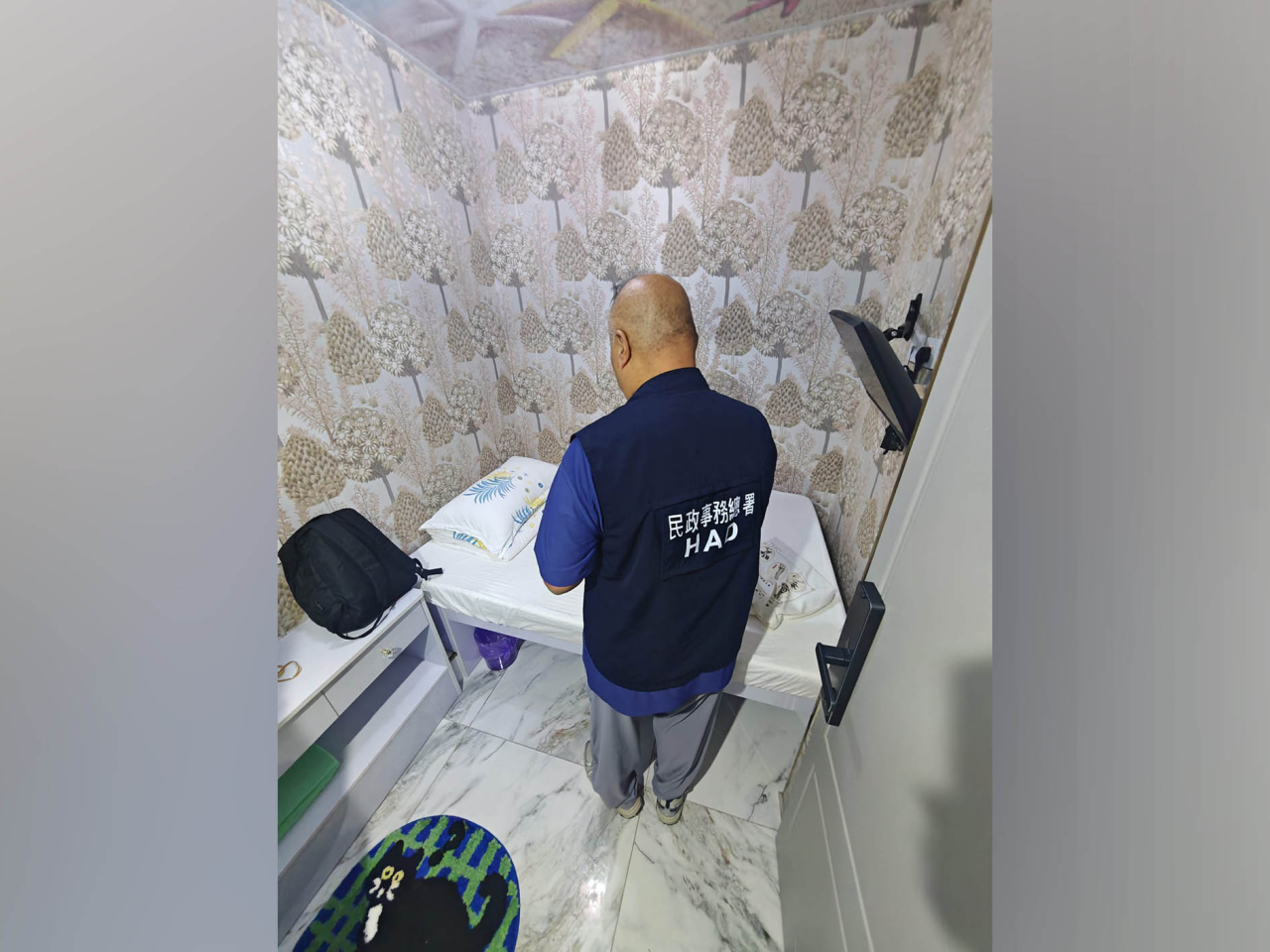 牌照事務處執法人員在一間懷疑無牌經營的賓館搜集證據。（政府新聞處）