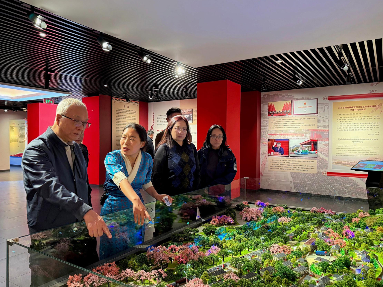 謝展寰（左一）在林芝市嘎拉村聽取人員介紹當地發展鄉村生態旅遊包括水果種植採摘園的情況。 （政府新聞處）