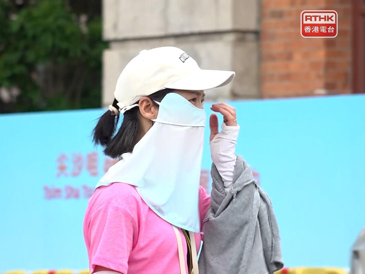 A woman wears a hat and arm protection sleeves to keep herself cool. Photo: RTHK