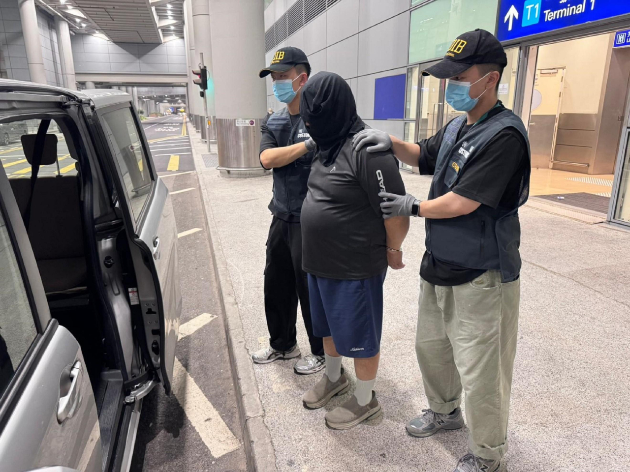 其中一名被捕男旅客被海關人員帶走。（政府新聞處）