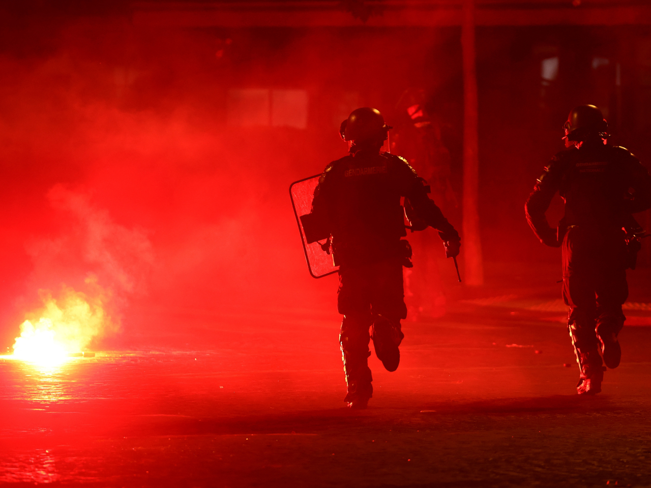 Police officers protect themselves from a flare after Paris St Germain fans hit the streets following their team's Champions League win over Arsenal. Photo: Reuters