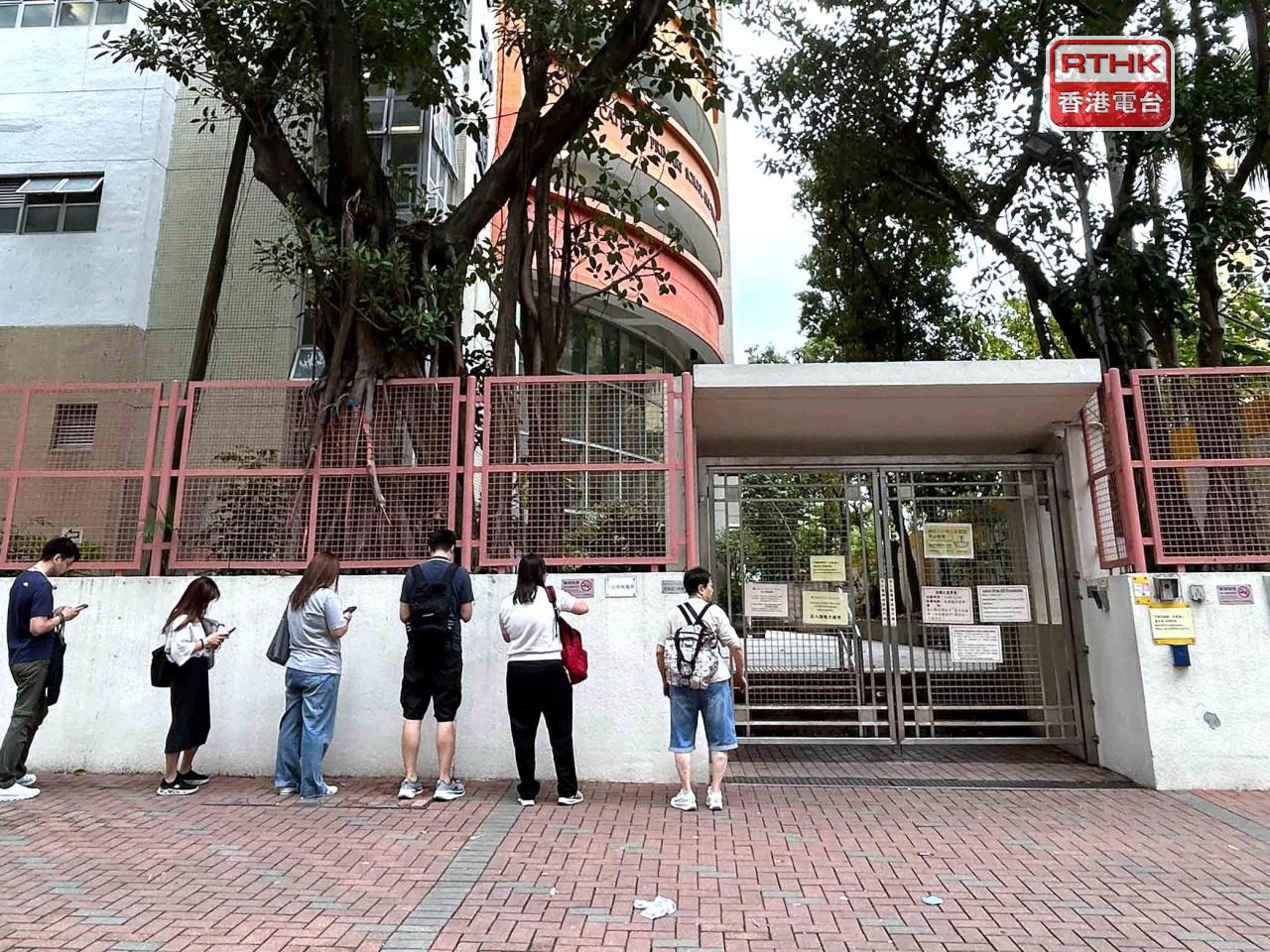 在油麻地一間小學，多位家長早上在門外排隊，等候「叩門」，希望為子女申請候補位。（鄧穎琳攝）