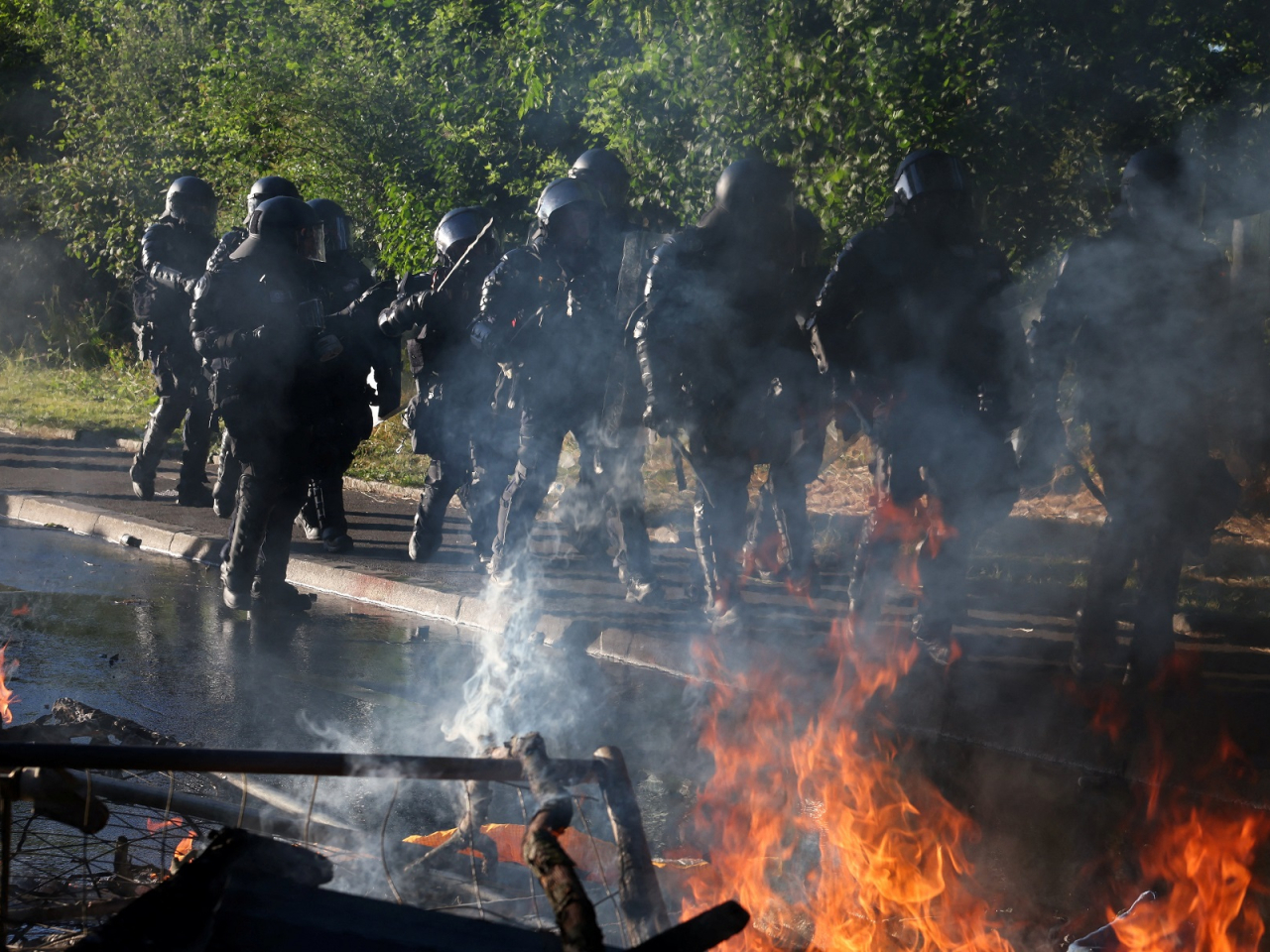 Riot police walk past a fire during a protest in Geneva against the upcoming G7 summit. Photo: Reuters