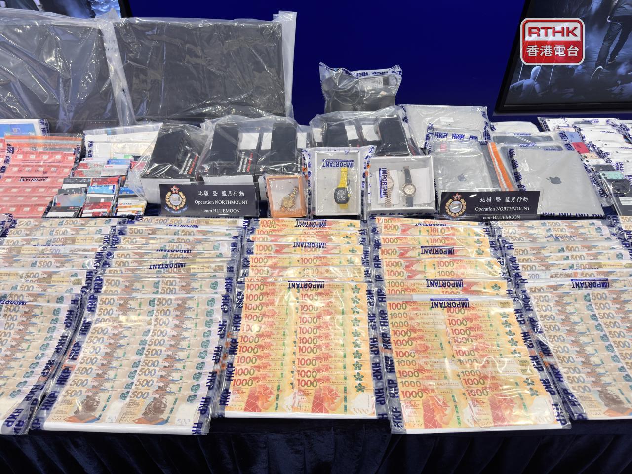 Police show the HK$1 million cash, watches and documents seized during three days of raids on eight premises. Photo: RTHK