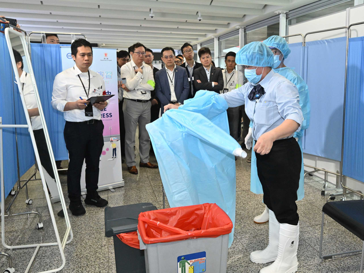 林文健（左三）、徐樂堅（左四）視察前線工作人員卸除個人防護裝備的程序及相關防護措施。（政府新聞處）