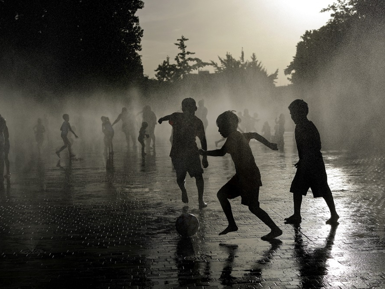 Children play football as they cool off in a water fountain in Madrid as Spain experiences a heatwave. Photo: AFP