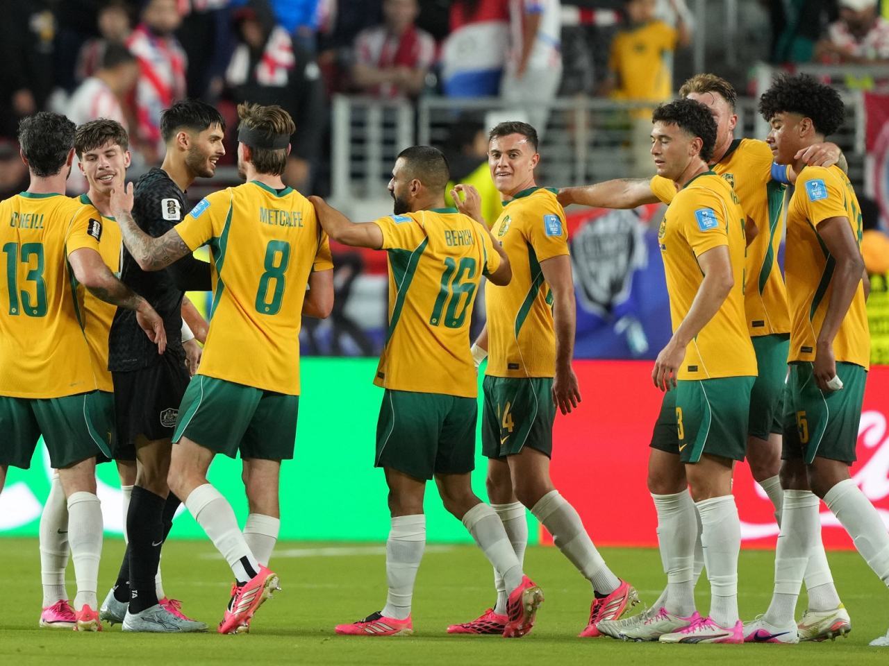 The Socceroos celebrate after they secure a place in the knockout rounds with a draw against Paraguay. Photo: Reuters