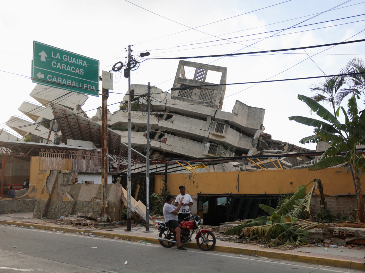 People speak as they gather next to damaged buildings at the site during rescue operations after earthquakes hit the country, in La Guaira, Venezuela. Photo Reuters