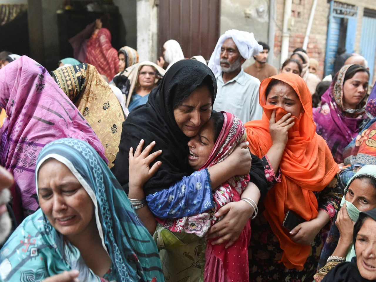 Distraught relatives comfort each other outside the tuition centre in Lahore. Photo: Reuters