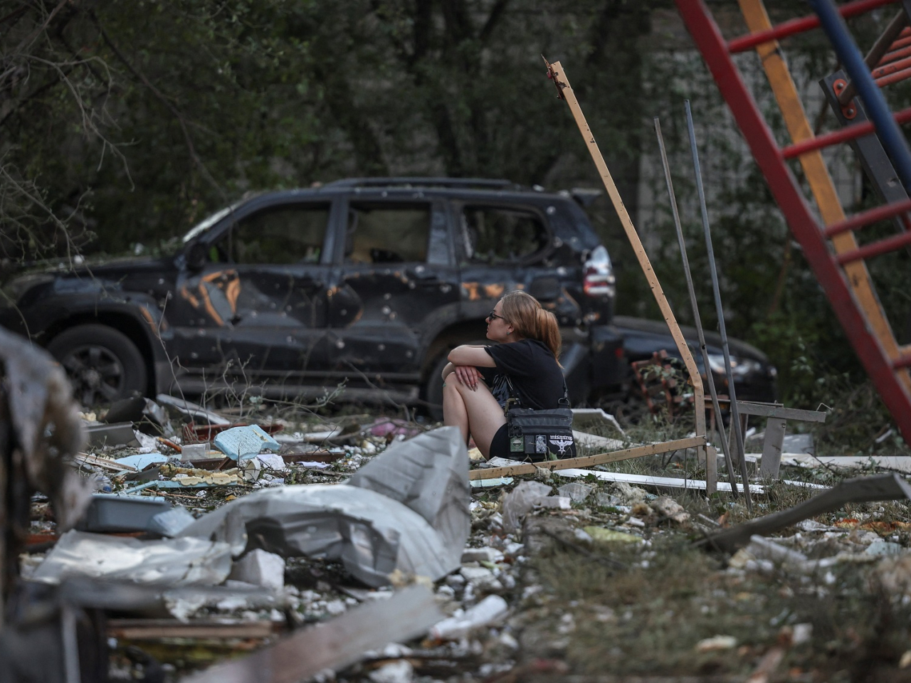 A woman sits in front of a damaged residential building in Kyiv. Photo: Reuters