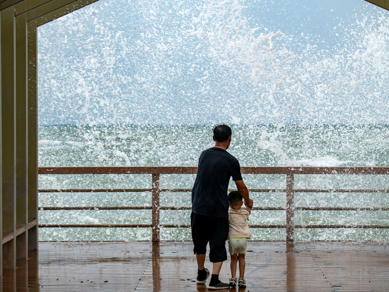 People watch waves crashing against the shore as Tropical Storm Maysak approaches Hainan. Photo: Reuters