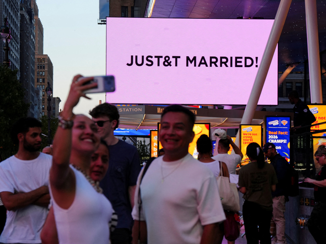 People take selfies next to a screen displaying a message referencing singer Taylor Swift and NFL star Travis Kelce outside Madison Square Garden. Photo: Reuters