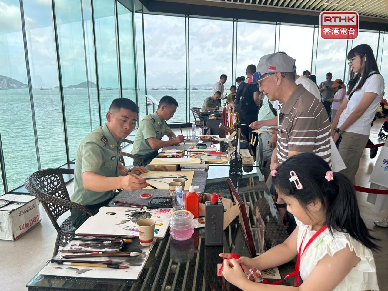 不少人到觀海長廊晀望軍艦及維港景色，並排隊領取官兵即席揮毫的書法或繪畫。（鄧穎琳攝）