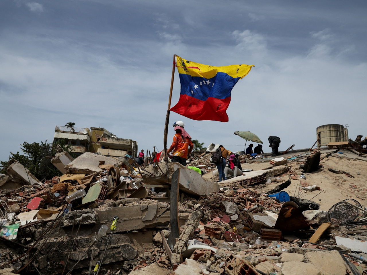 A flag of Venezuela flutters as rescuers work at the site of a collapsed building in La Guaira. Photo: Reuters