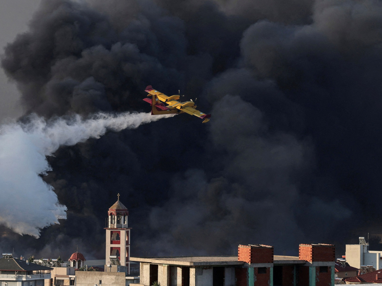 A firefighting plane drops water at a burning recycling factory in Oreokastro, on the outskirts of Thessaloniki, Greece. Photo: Reuters