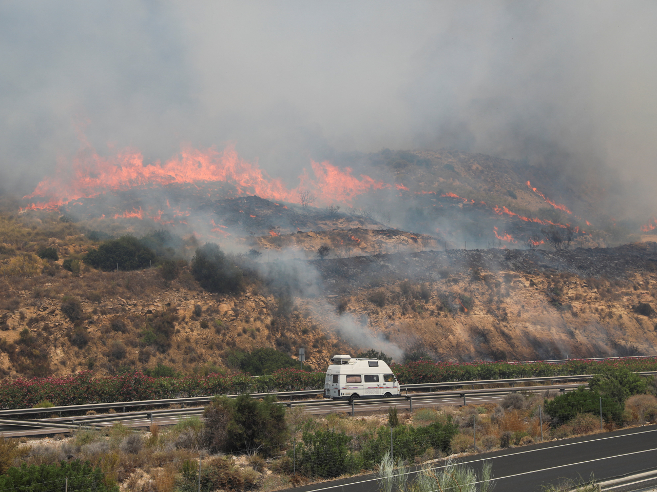 A van drives along the A7 highway as a wildfire approaches in the vicinity of Los Gallardos, in Almeria, Spain. Photo: Reuters