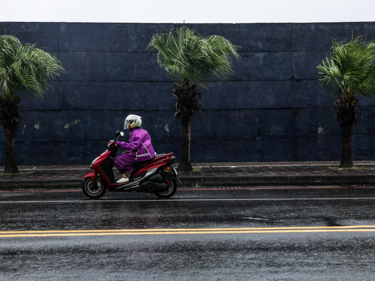 在基隆，有男子騎電單車在雨中行駛。（法新社）