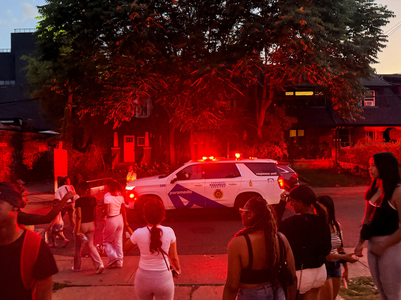 A police vehicle makes its way as people gather near the scene after a deadly shooting, at a salsa-themed street festival in Toronto. Photo: Reuters