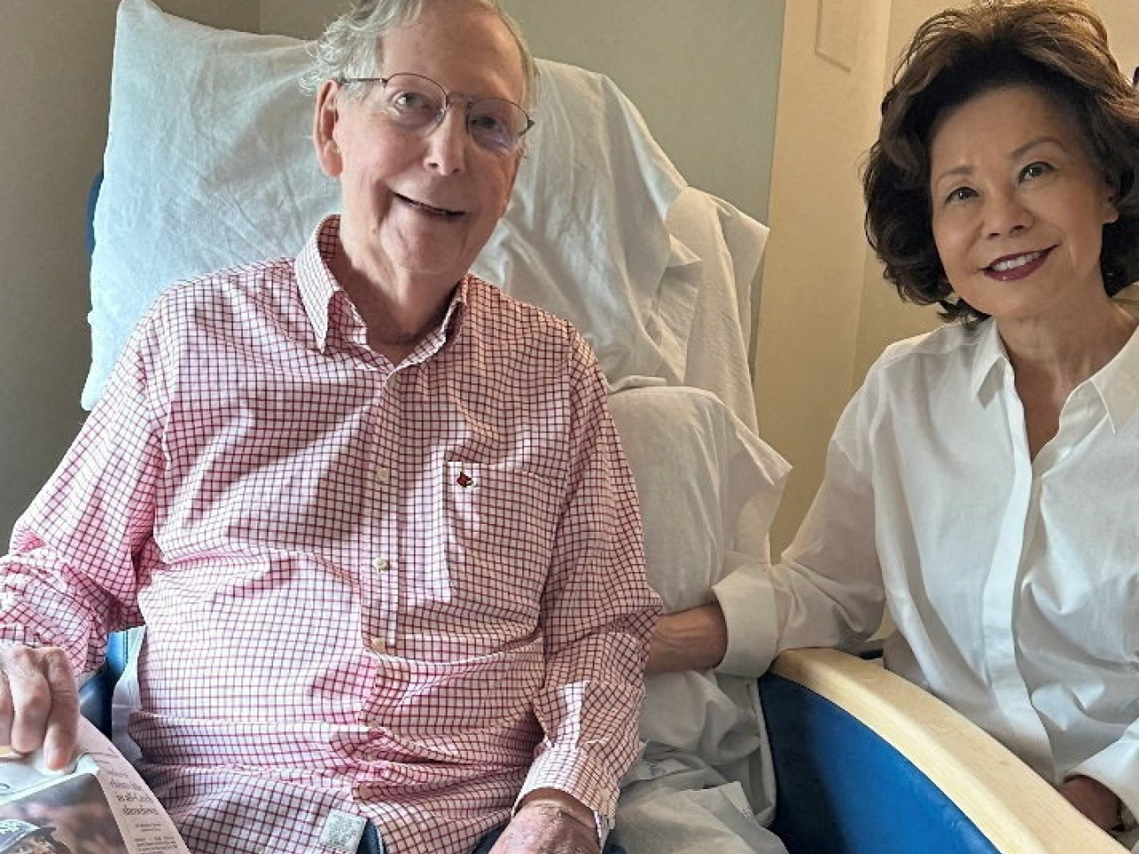 Mitch McConnell sits with his wife Elaine Chao, while holding what appears to be the July 12 sports section of the Washington Post in a photograph released by his office. Photo: handout via Reuters