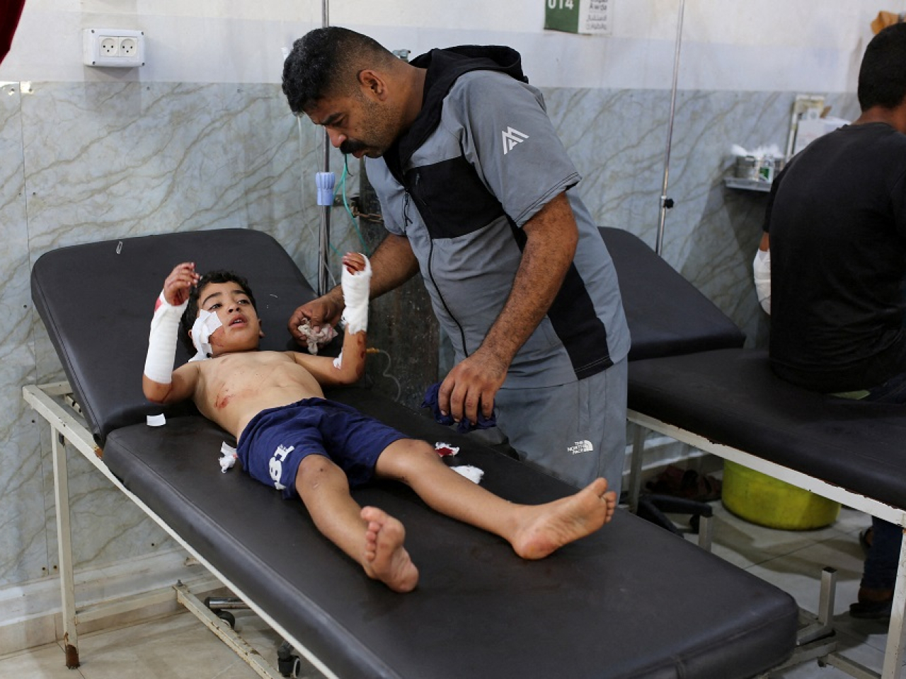 A young boy injured in the air strike is tended to by his father. Photo: Reuters