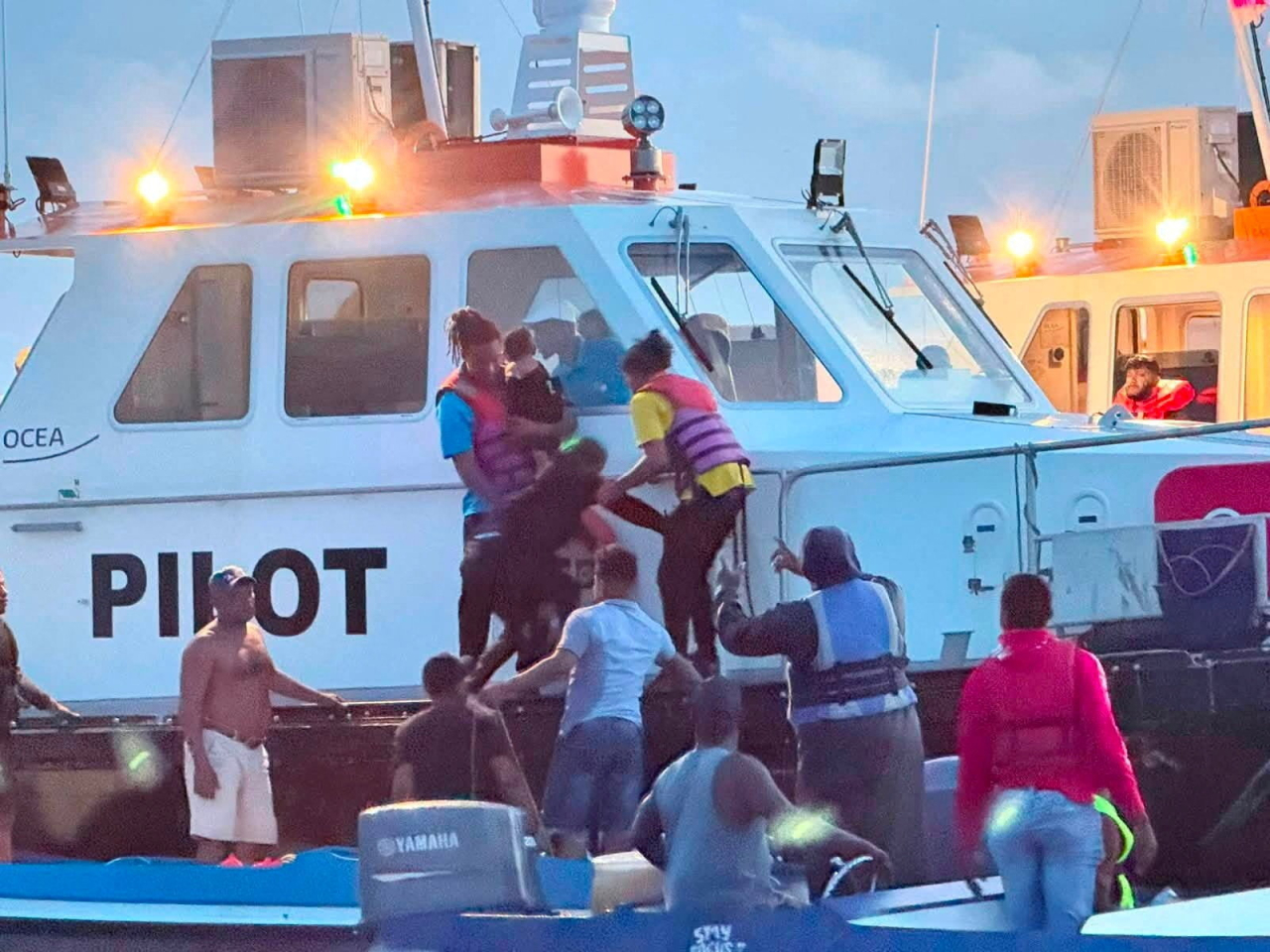 Ferry passengers are helped aboard a rescue boat off the coast of Guyana. Photo: Reuters