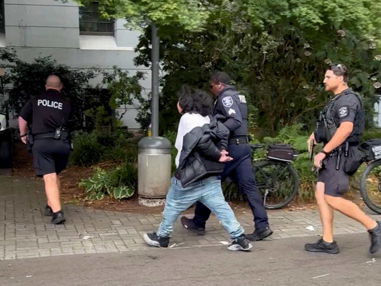 Seattle Police officers detain a man following the shooting which left three dead and four wounded. Image: Justin Reinhard via Reuters