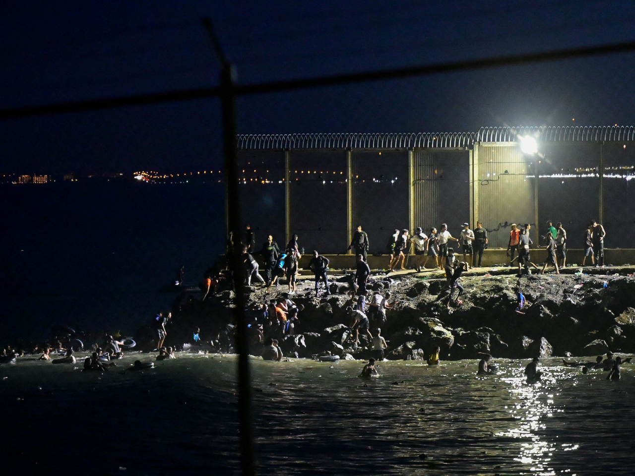 Migrants swim into Ceuta from Morocco and gather near the border fence of the Spanish enclave. Photo: Reuters