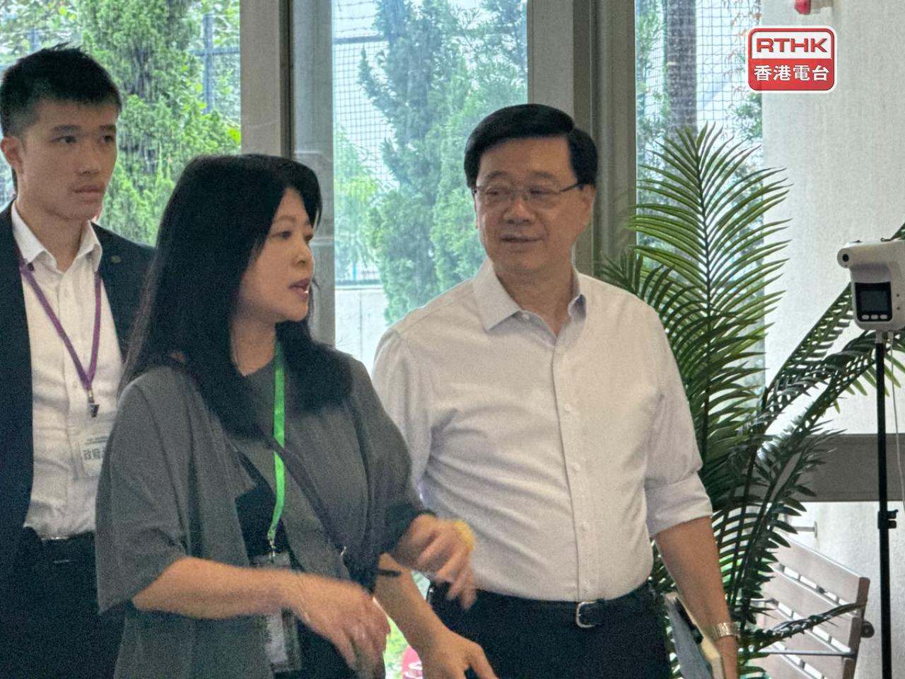 李家超（右）抵達南屯門官立中學，準備出席首場諮詢會。（實習記者鄭凱安攝）