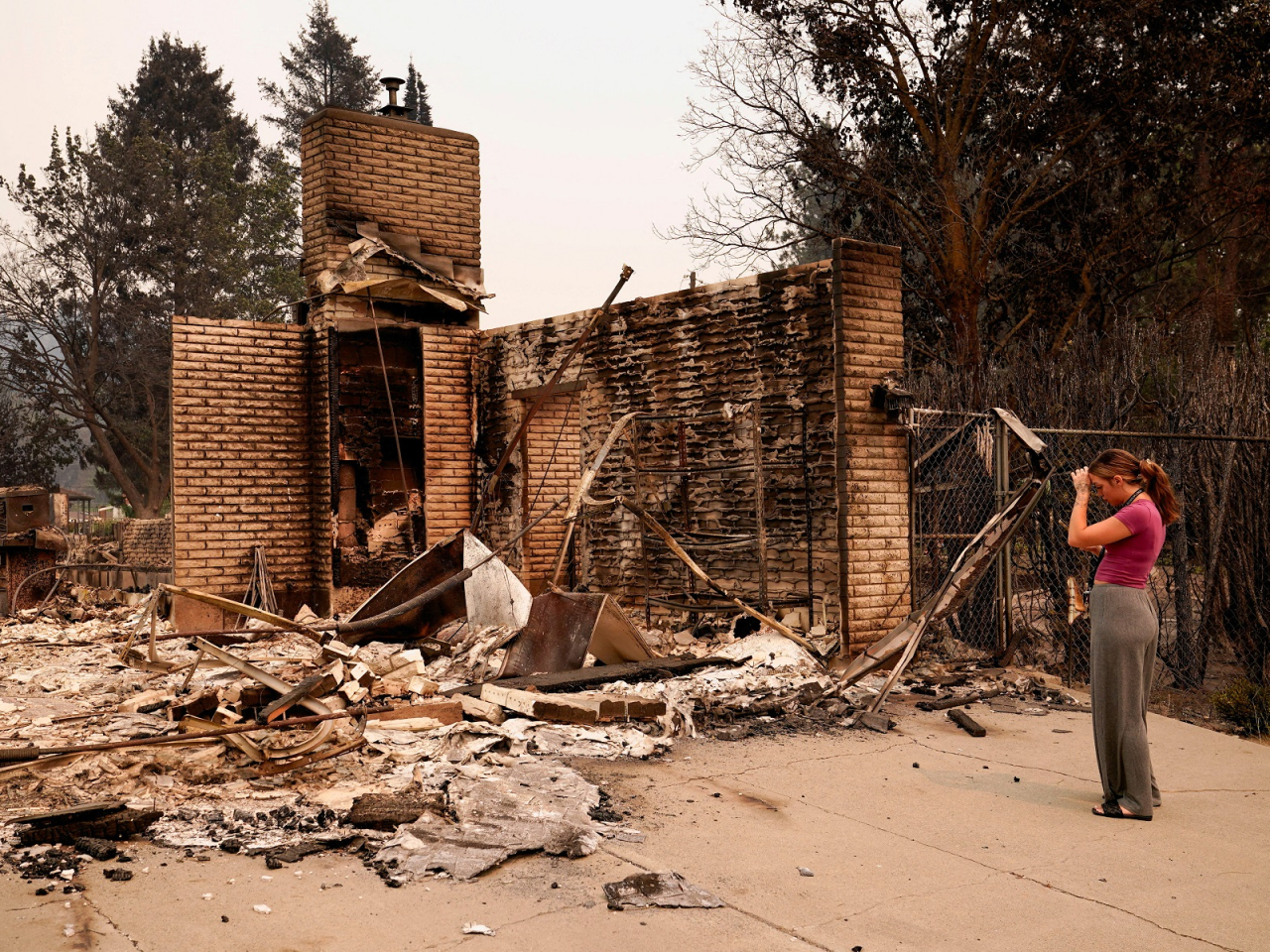 A woman stands in front of her home after it was destroyed by a wildfire in Spokane, Washington. Photo: Reuters