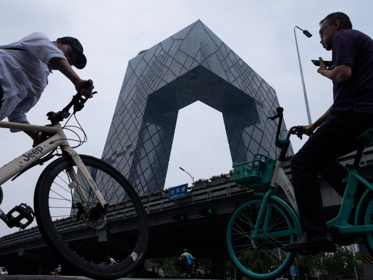 The iconic CCTV Headquarters building towers over cyclists in Beijing's Central Business District. File Photo: Reuters