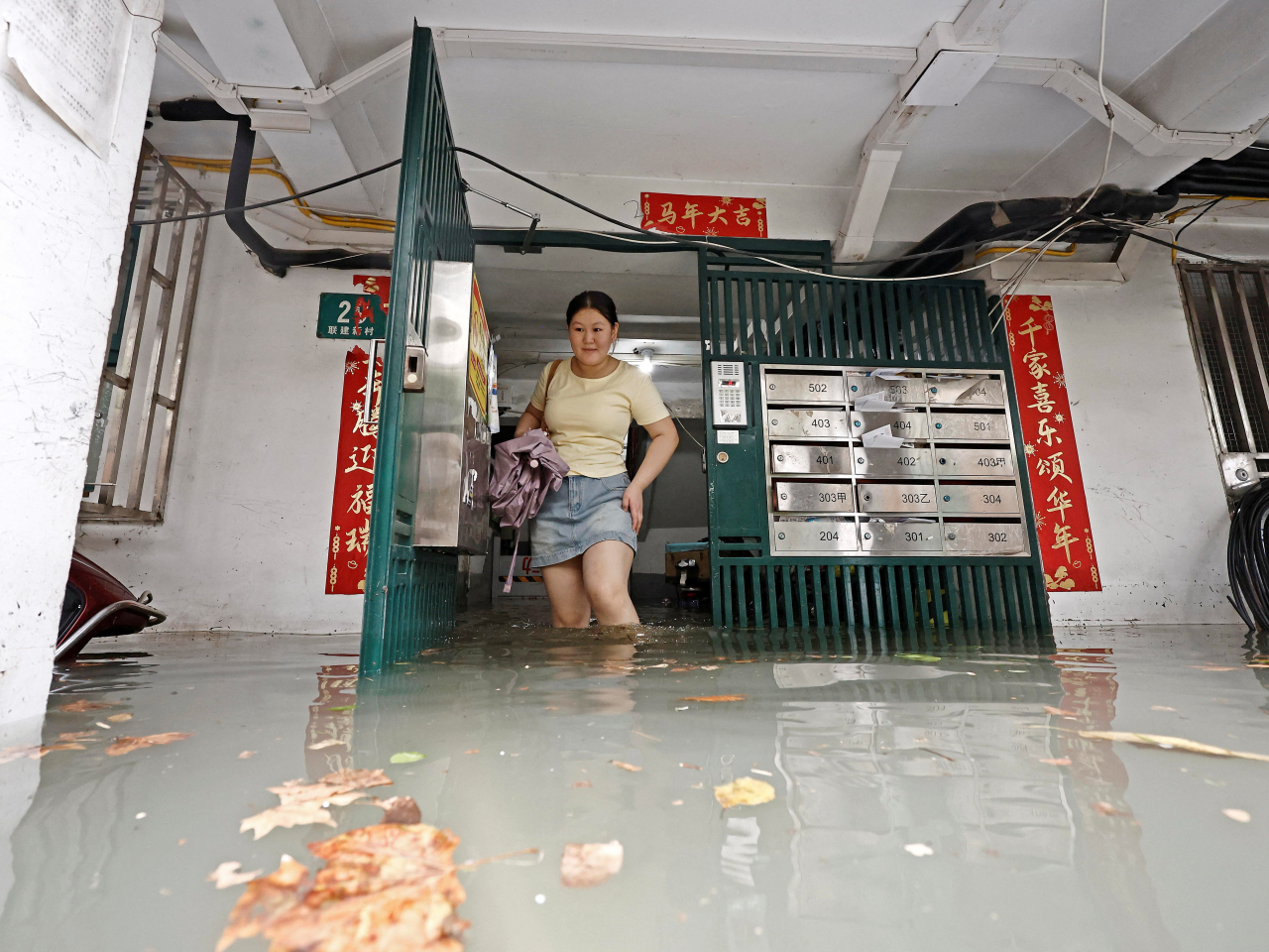 A Shanghai resident wades through floodwaters in her building as Typhoon Dolphin approaches on Sunday. File photo: Reuters