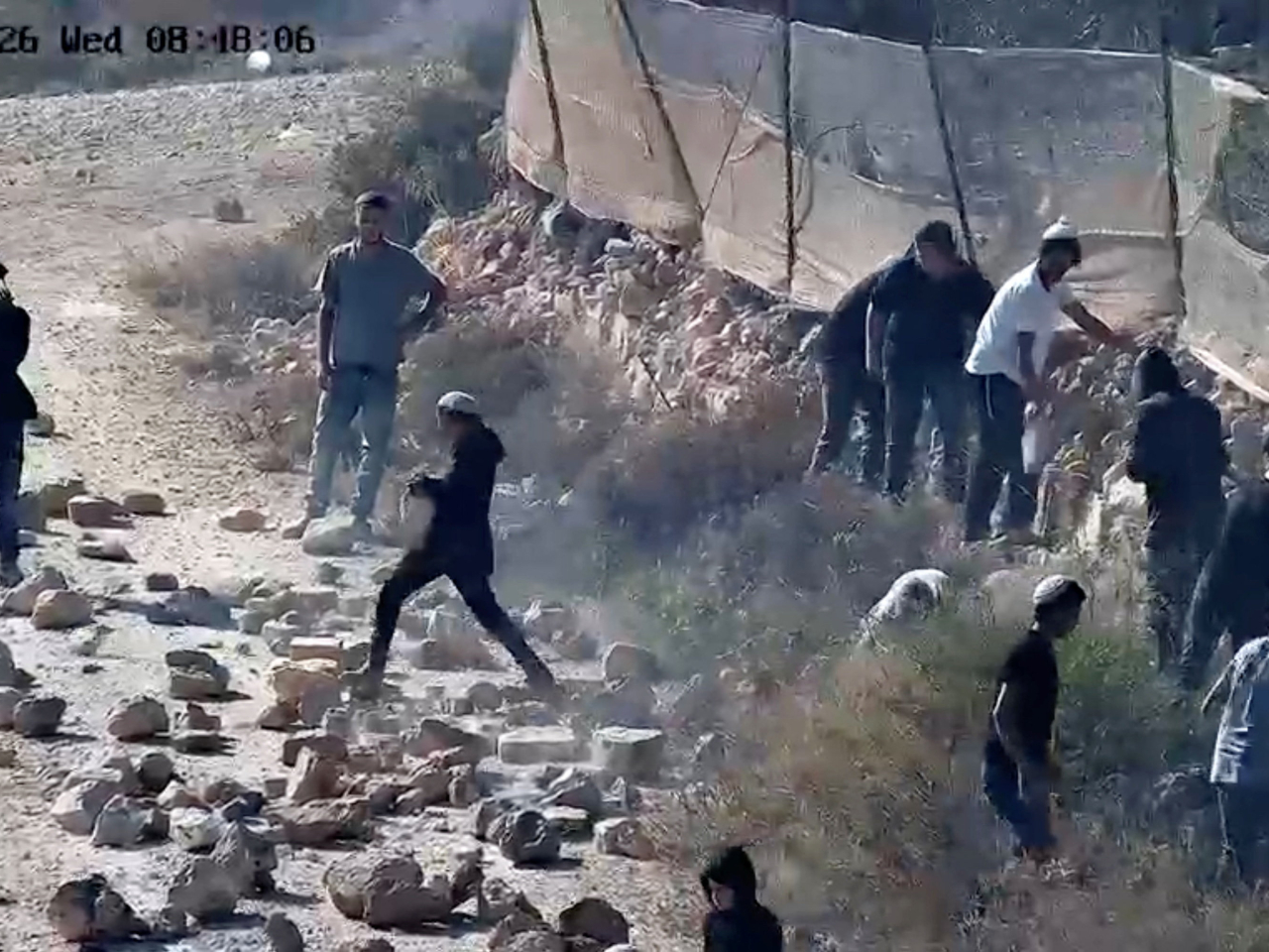 Settlers throw rocks onto a road in Qusra in the West Bank after the Israeli military failed to disperse them. Photo: Reuters