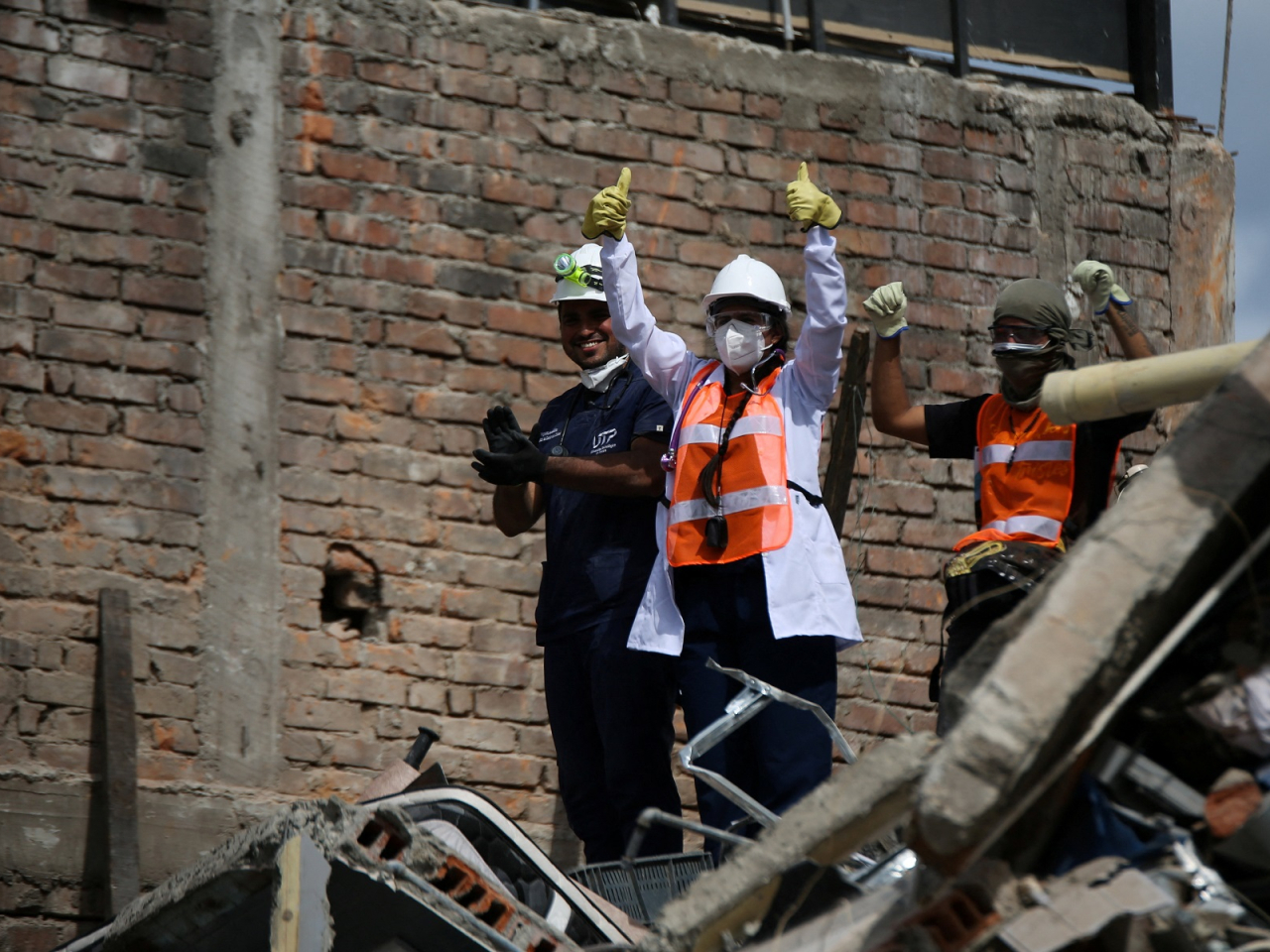 Rescuers react after hearing someone alive beneath the rubble at the site of a damaged building in Pereira. Photo: Reuters