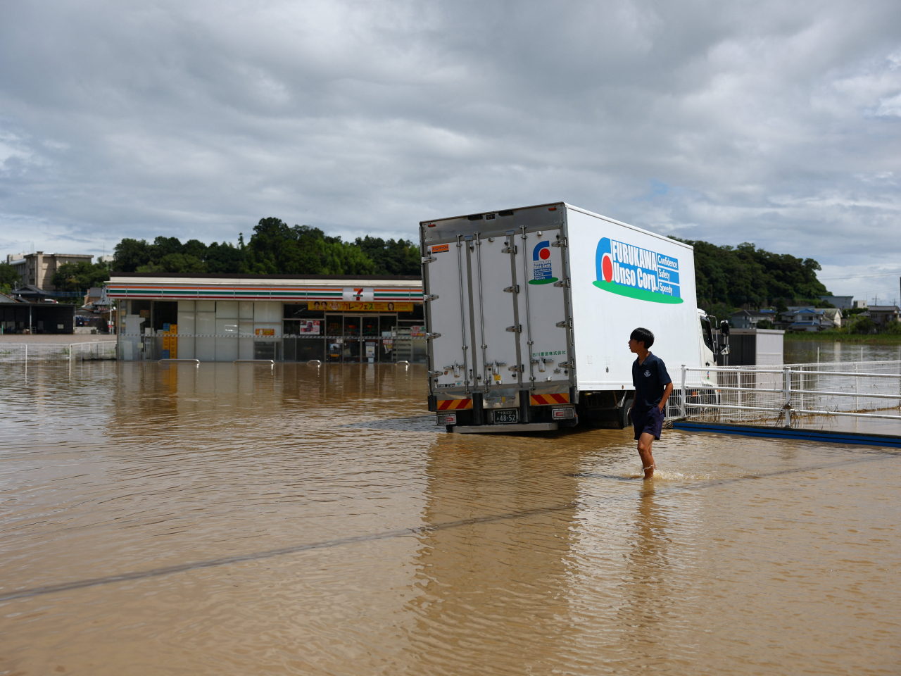 A resident treads a lonely path in a sea of floodwater in Oamishirasato, Chiba. Photo: Reuters