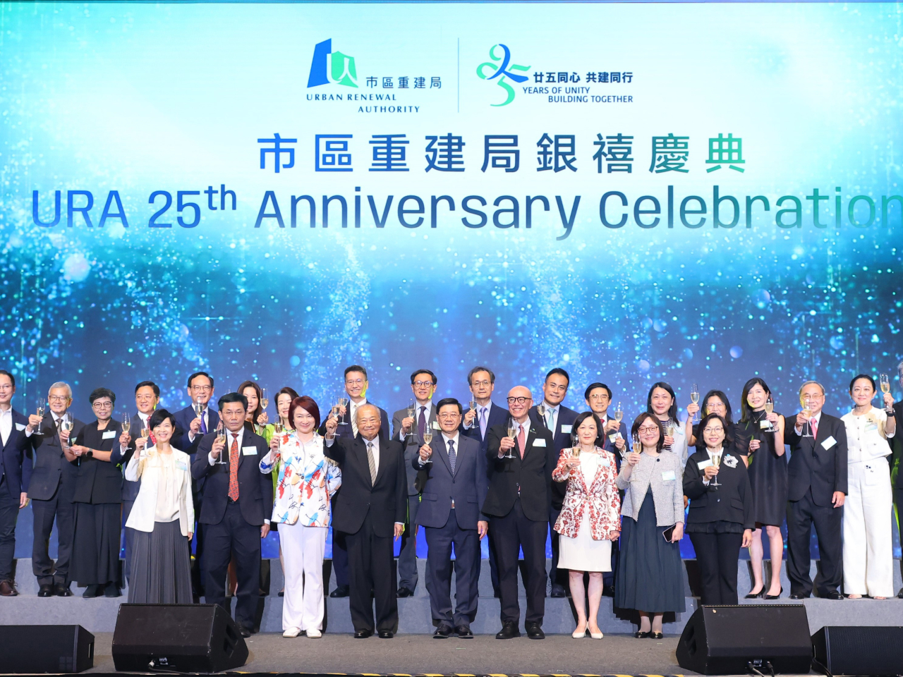 李家超（前排中）及周松崗（前排左四）為市建局銀禧慶典主禮，並與其他嘉賓一同主持祝酒儀式。（市建局提供）