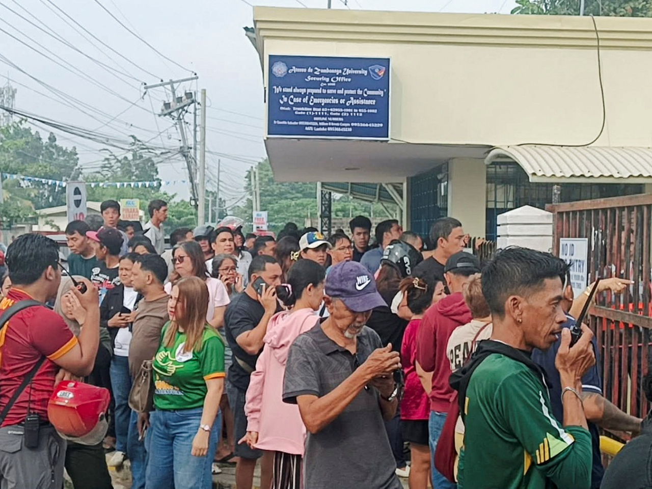 People stand outside Ateneo de Zamboanga University after a Grade 9 student allegedly shot dead a Grade 10 schoolmate before turning the gun on himself. Photo: Reuters