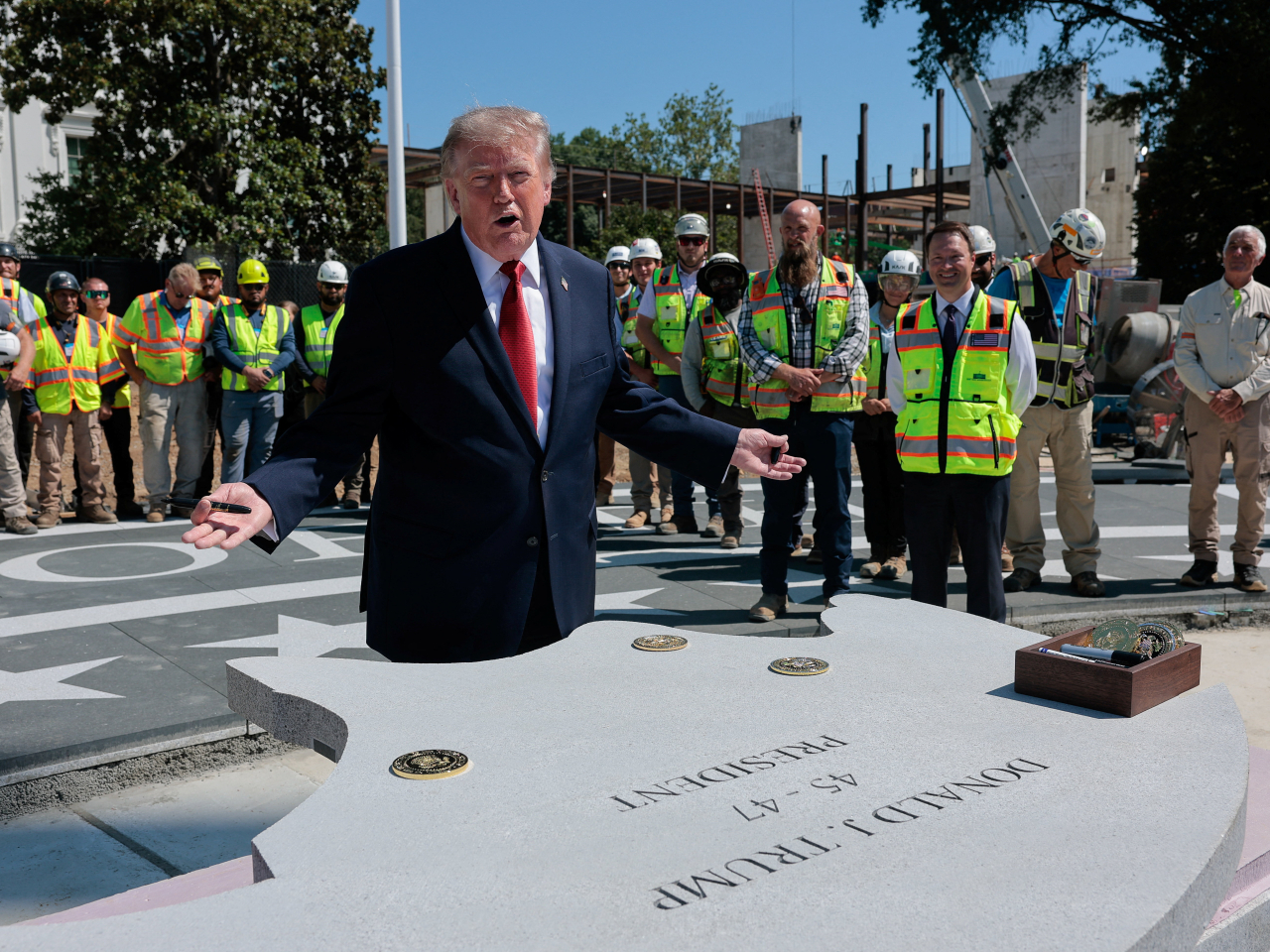 Donald Trump shows off a stone, which names him as the 45-47 president, that will be inserted into the helipad. Photo: Reuters