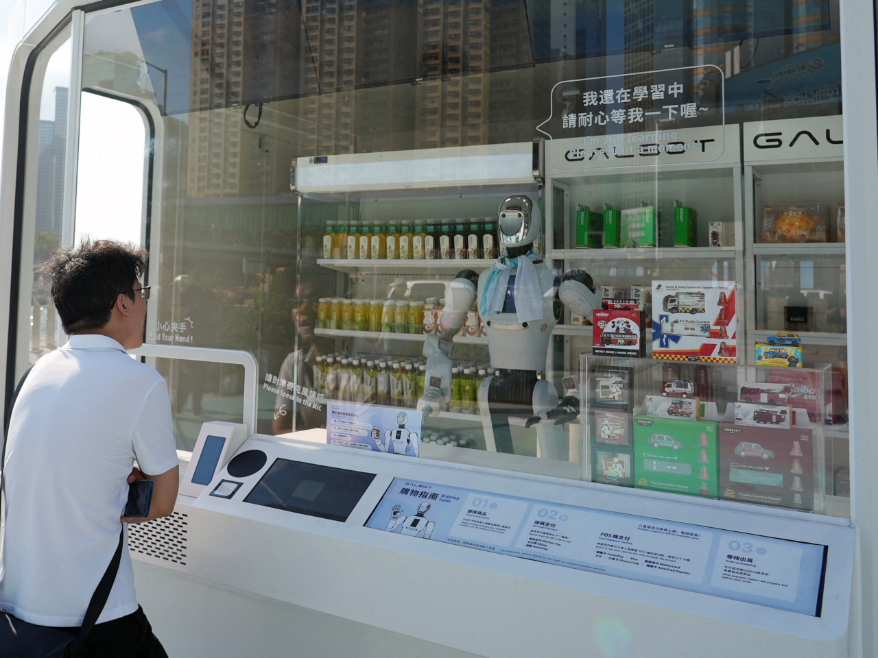 A man interacts with Xiao Gai, a humanoid robot, at a Galbot Store in the city. Photo: Reuters