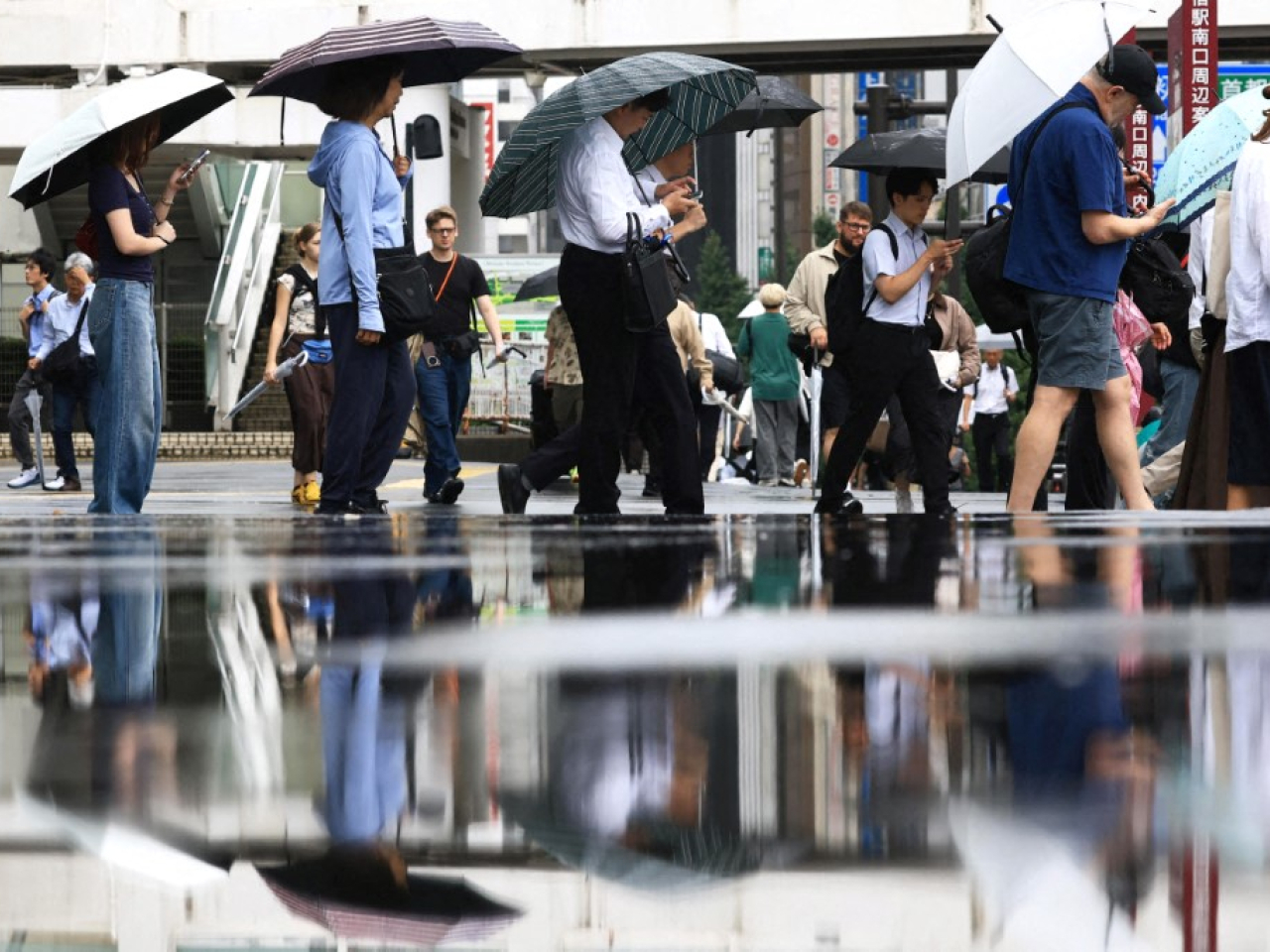 東京下雨，民眾外出都帶備雨具。（法新社）