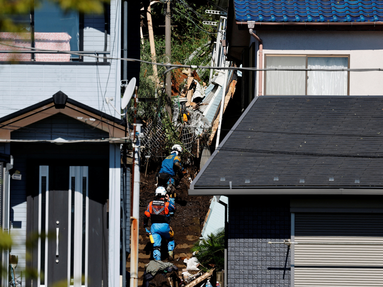 Rescuers search for a missing person at houses hit by a landslide triggered by Typhoon Dujuan in Miura, Kanagawa prefecture. Photo: Reuters