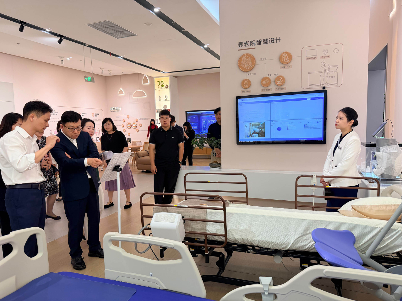 孫玉菡（左二）參觀上海市養老科技產業園的展示區，並聽取工作人員講解如何操作電動護理床。（政府新聞處）