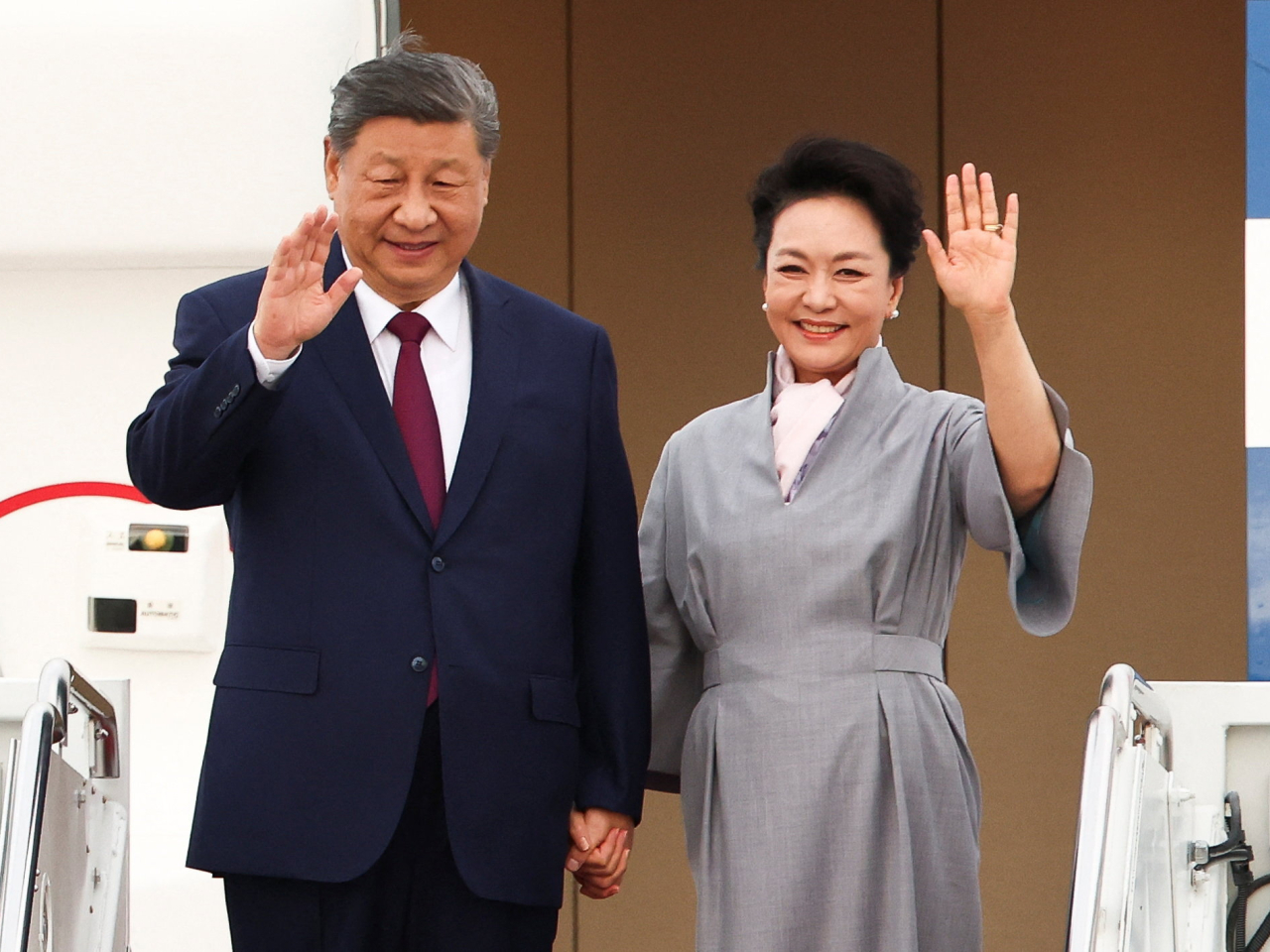 習近平伉儷在落機前向在場人士揮手。（路透社）