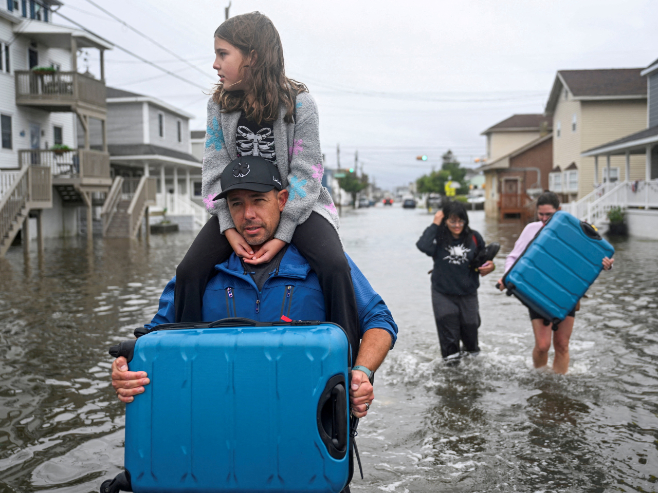 A family carrying personal belongings walk on a flooded street after heavy rain from a nor'easter fell as a strong coastal storm batters the US northeast. Photo: Reuters