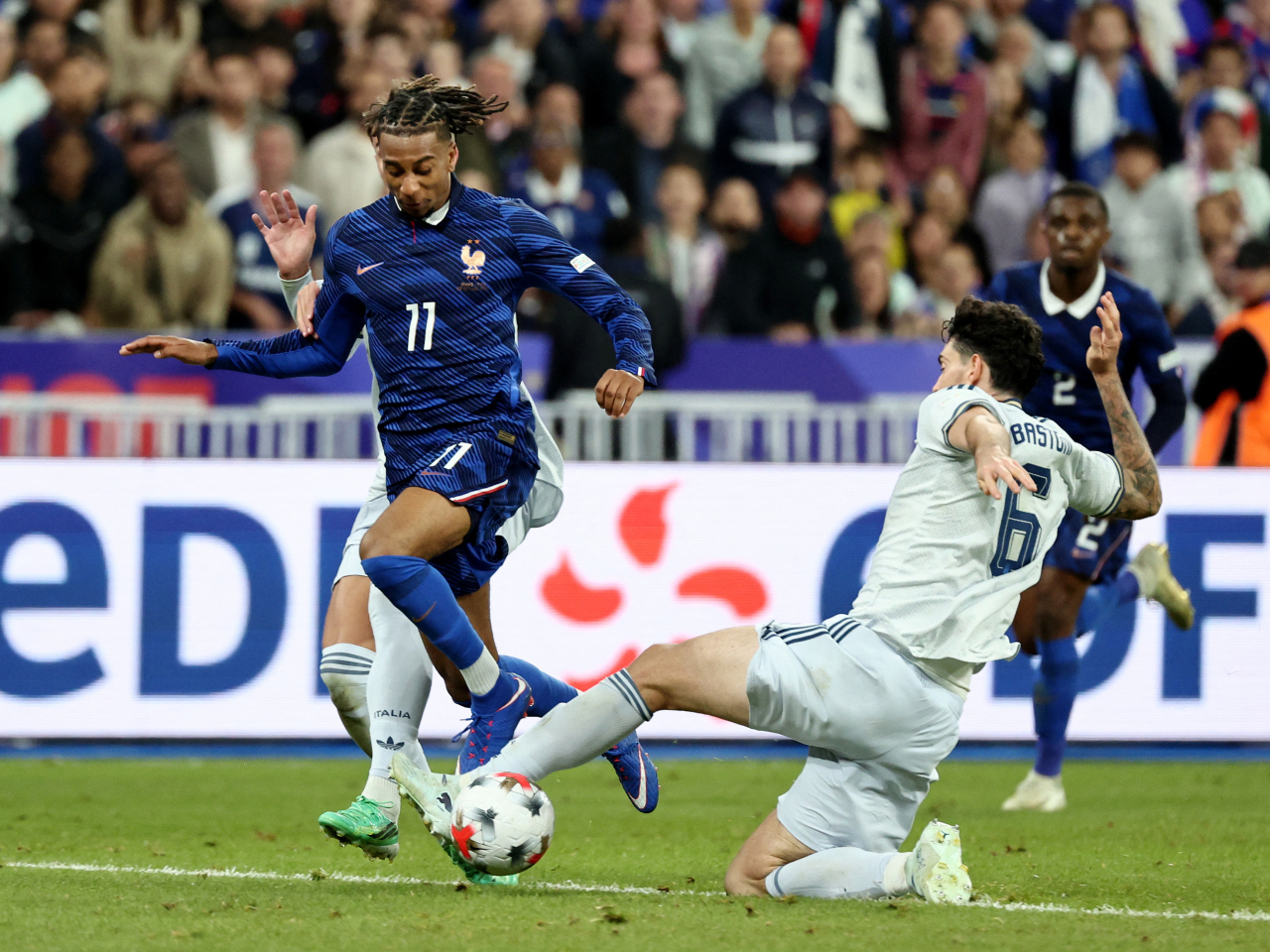 Italy's Alessandro Bastoni slides in to stop a Michael Olise attack in the Stade de France near Paris. Photo: Reuters