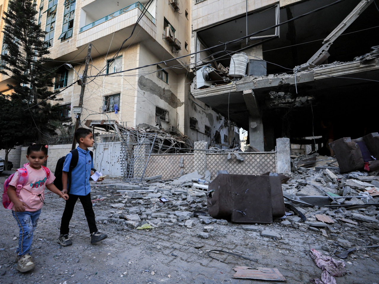 Palestinian children walk past the site of an Israeli strike on an apartment building in Gaza City. Photo: Reuters