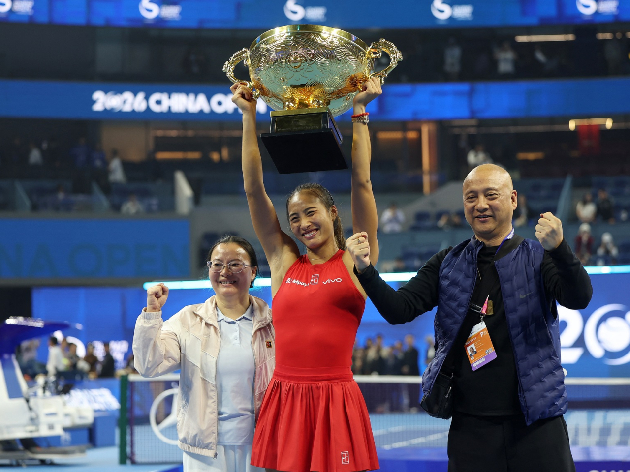 Flanked by her parents, Zheng Qinwen lifts the China Open trophy in Beijing on Sunday. Photo: Reuters