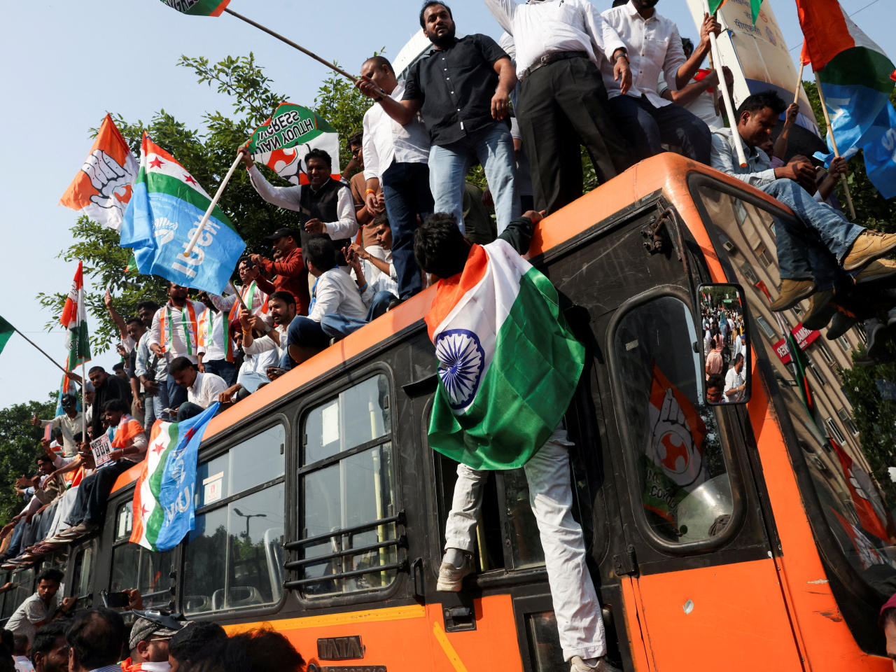 Supporters of the opposition parties climb on top of a bus with placards and flags while marching to the Supreme Court in New Delhi. Photo: Reuters