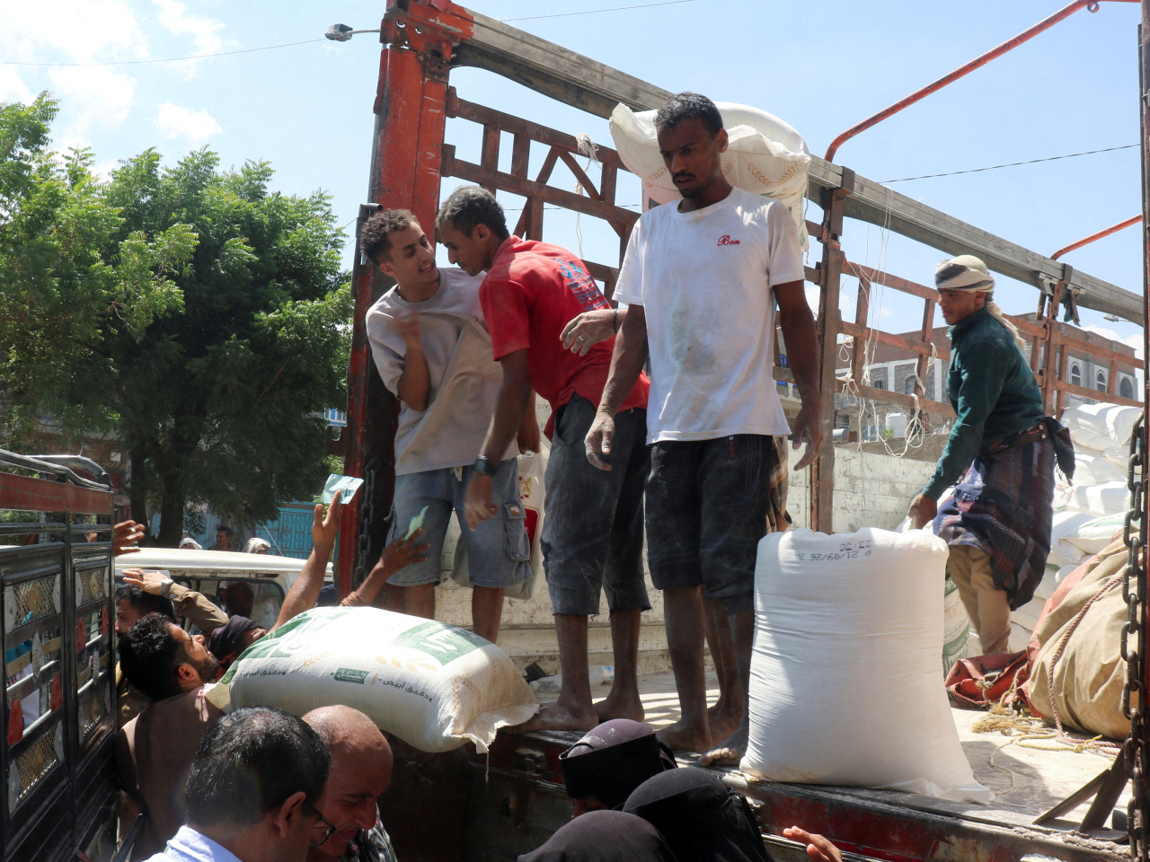Shop workers sell sacks of wheat flour from a truck as clashes between Houthis fighters and Saudi-backed Yemeni forces continues in Taiz, Yemen. Photo: Reuters