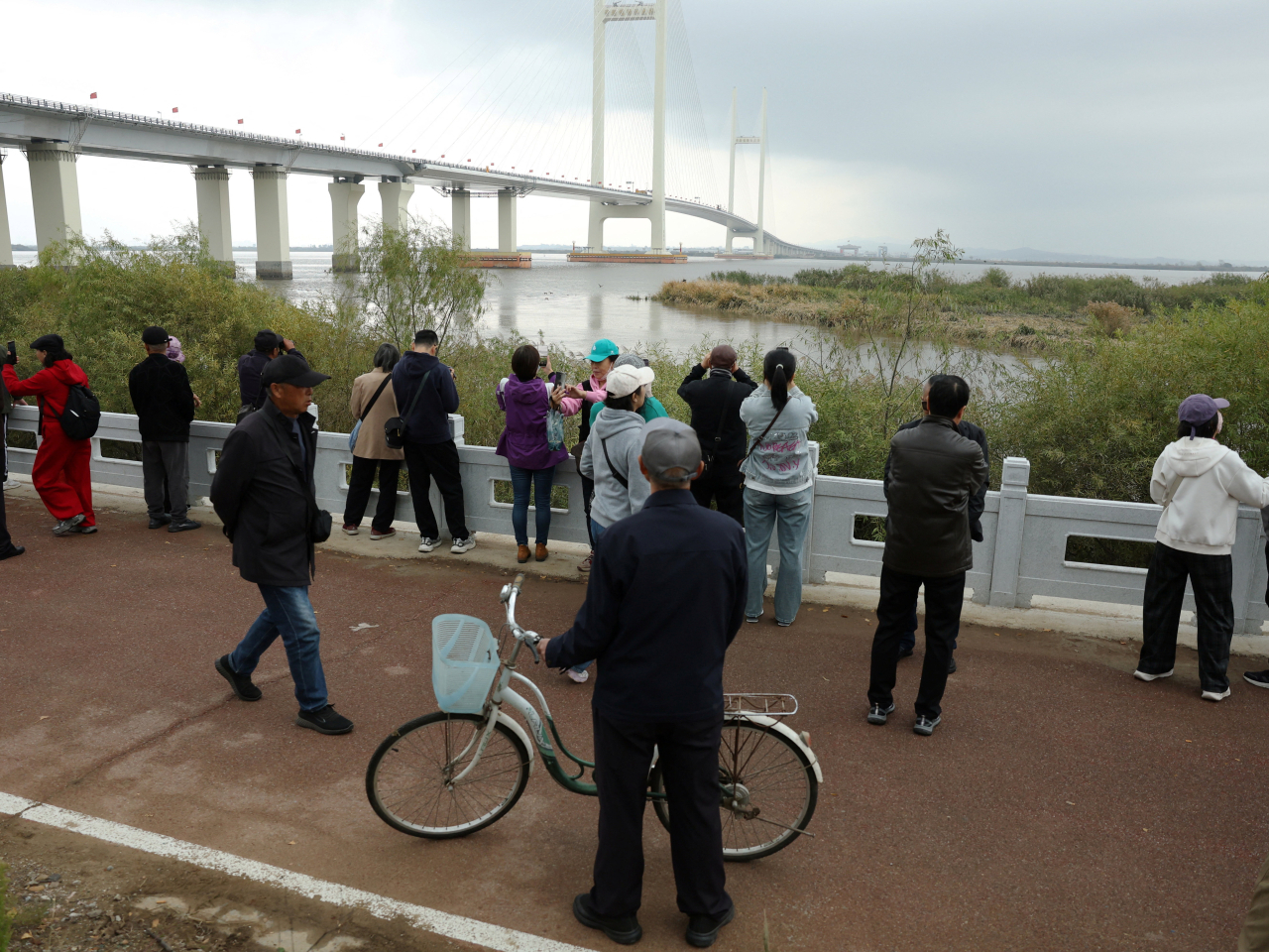 Mainland residents in Dandong, Liaoning, watch for movements on the DPRK side of the New Yalu River Bridge. Photo: Reuters